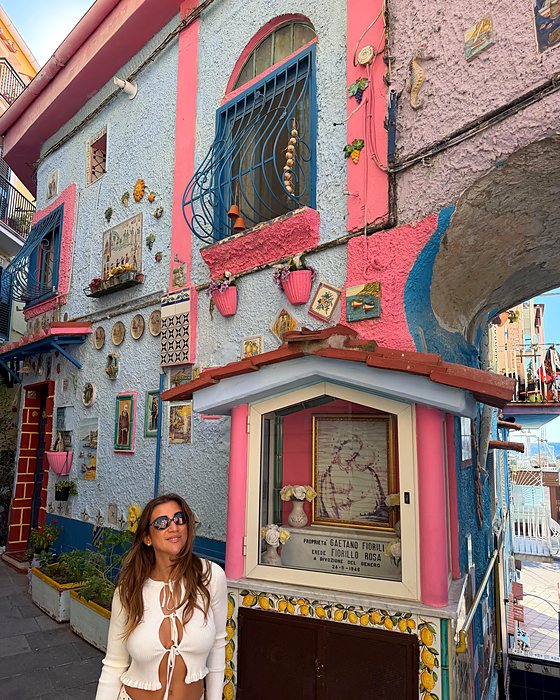 Una casa rosa e azzurra a Vietri con un'edicola e tante ceramiche sulla facciata