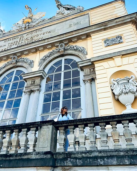 Un edificio storico con statue e una balconata, con una persona affacciata