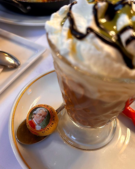 Un bicchiere con panna e cioccolato e una Palla di Mozart sul cucchiaino